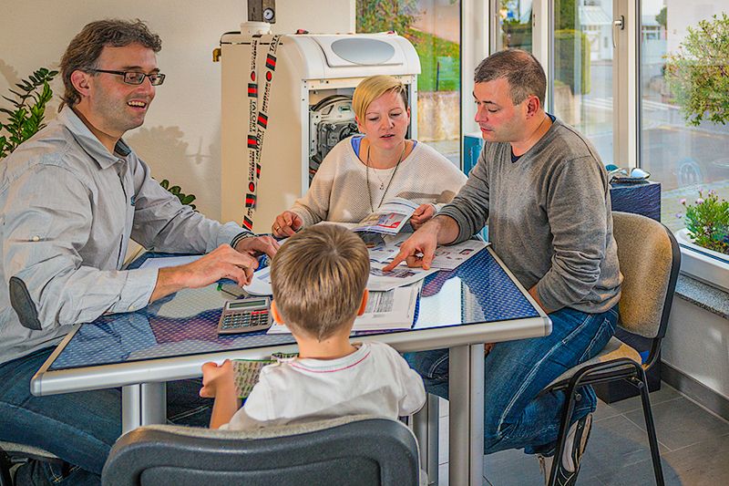 Glückliche Familie sitzt gemeinsam am Tisch und wird beraten